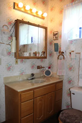 Bathroom vanity featuring a light-toned countertop with an integrated sink, wood-finish cabinetry, and a wall-mounted medicine cabinet with a mirrored front