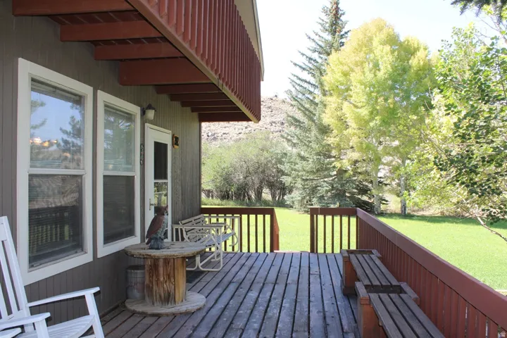 Expansive wood deck with a red railing and integrated benches, offering views of the surrounding natural landscape