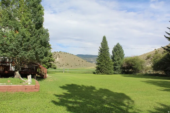 Expansive green lawn with mature trees and a distant hillside backdrop