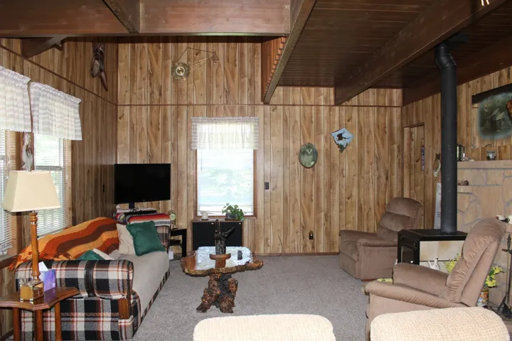 Inviting living area featuring wood-paneled walls and a wood-finish ceiling with exposed beams