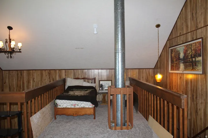 Loft area featuring wood-panel walls, sloped ceilings, and carpet flooring