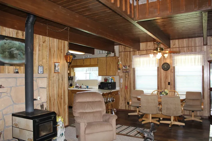 Open-concept living space featuring wood-finish flooring, wood paneling, and exposed wood beam ceilings