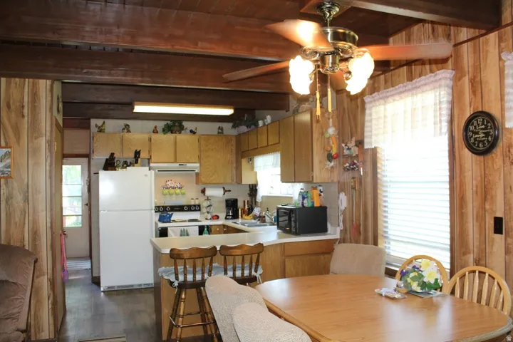Kitchen area featuring light wood-finish cabinetry and a white appliance suite