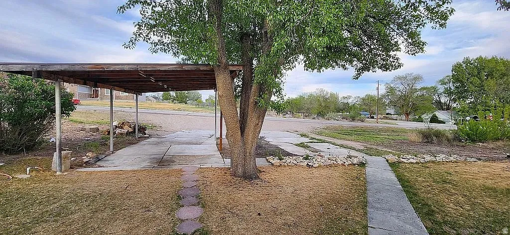 Paved driveway leading to a covered carport with metal supports