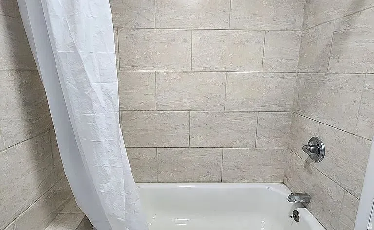 Bathtub with neutral-toned tiled surround and chrome fixtures