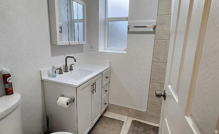 Bathroom featuring a white vanity with an integrated sink, brushed nickel faucet, and shaker-style cabinetry