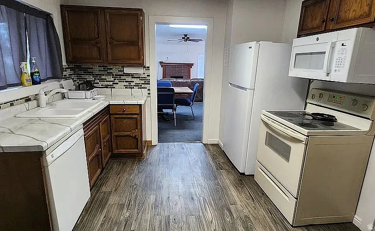Kitchen featuring wood-finish flooring, wood cabinetry, patterned tile backsplash, and light-toned countertops