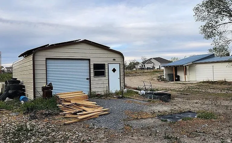 Detached metal-sided garage building with a roll-up door and side entry door