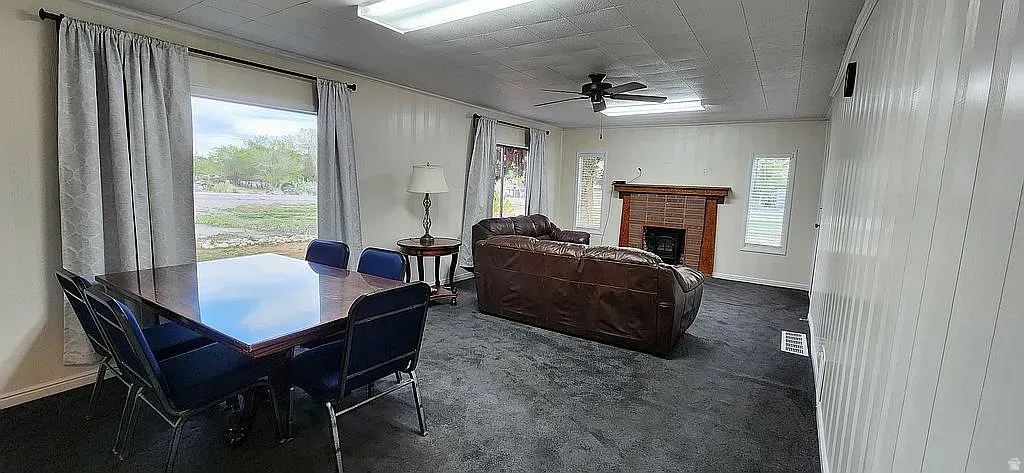 Spacious interior featuring a brick fireplace with a wood mantel, overhead fluorescent lighting, and a ceiling fan