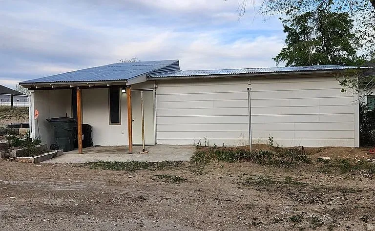 Property exterior with white siding and a corrugated metal roof