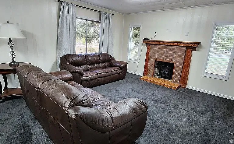 Living area featuring a brick fireplace with a wood mantle, wood-burning insert, and tile hearth
