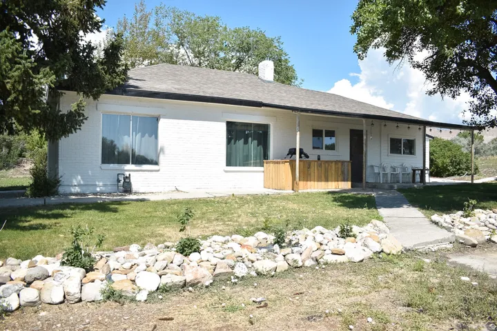 White brick ranch-style exterior with a dark shingle roof