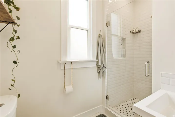 Glass-enclosed shower featuring white subway tile surround and a contrasting penny tile floor
