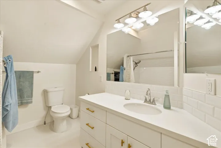 Contemporary bathroom featuring a white vanity with gold-tone hardware, a white countertop with an integrated sink, a large mirror, and subway tile backsplash