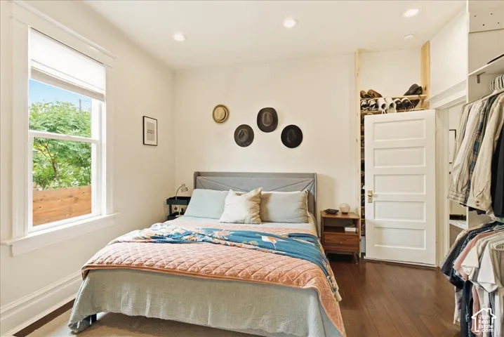 Bedroom featuring wood-finish flooring, recessed lighting, a window with exterior views, and a closet with built-in shelving