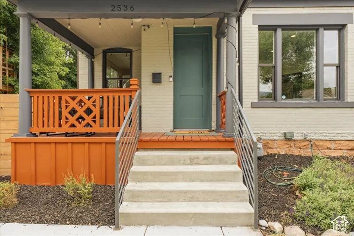 Inviting front porch with concrete steps, modern metal railings, a deep green entry door, and a decorative wood railing