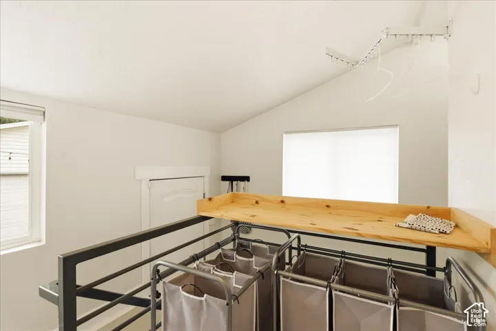Bright loft space featuring a vaulted ceiling and an integrated wood-finish countertop