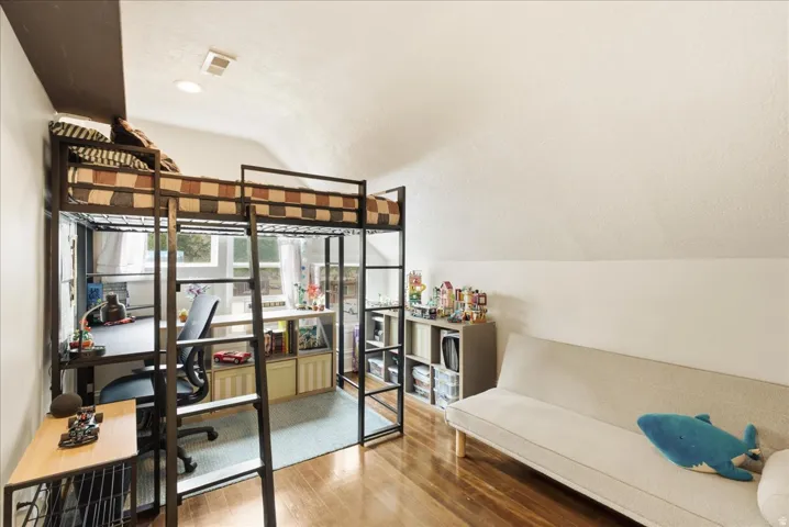 Loft-style bed frame with an integrated desk area, multiple windows, recessed lighting, and wood-finish flooring