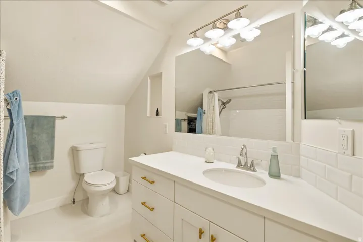 Contemporary bathroom featuring a white vanity with gold-tone hardware, a white countertop with an integrated sink, a large mirror, and subway tile backsplash