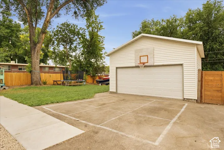 Detached garage with horizontal siding, a single overhead door, and an attached basketball hoop