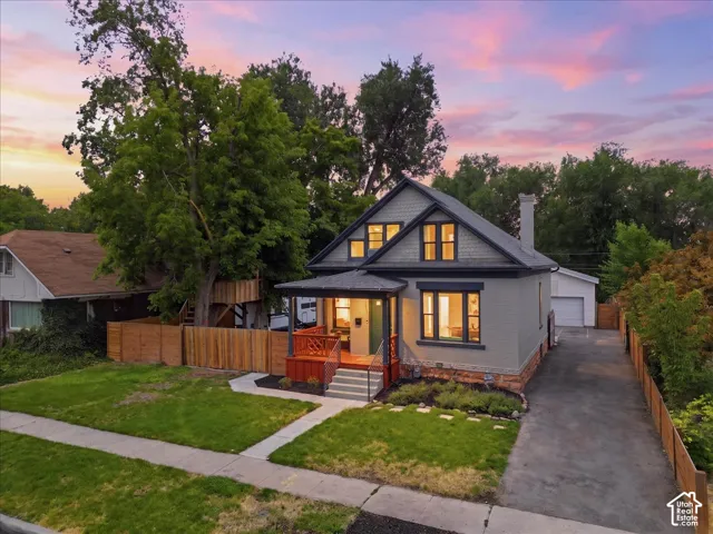 Charming residence featuring a covered front porch with a dark railing and red-toned wood accents