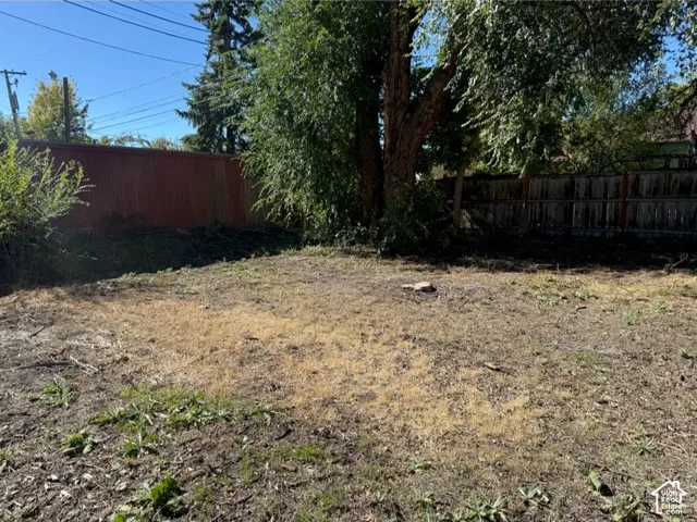 Side yard featuring mature trees and wood-panel fencing