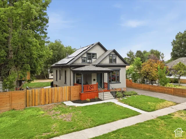 Two-story residence featuring a covered front porch, an asphalt shingle roof with solar panels, and a gabled dormer