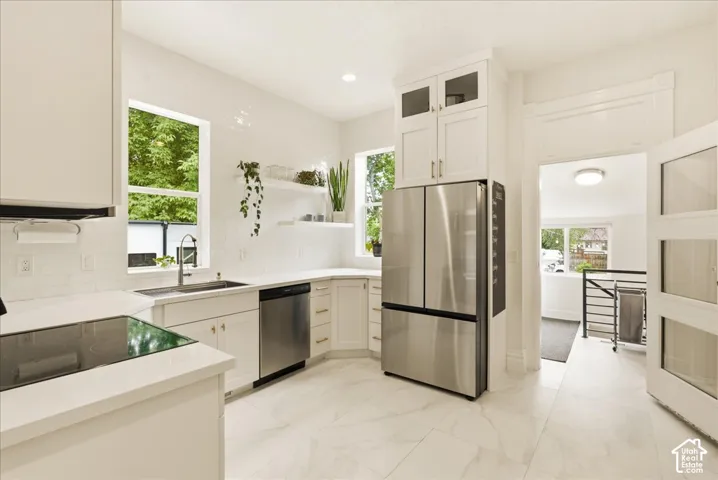 Modern kitchen featuring white cabinetry, stainless steel appliances, a built-in cooktop, and a subway tile backsplash