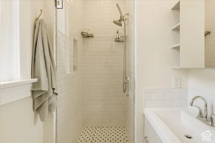 Shower with white subway tile surround and black and white penny tile flooring, featuring a built-in shower niche