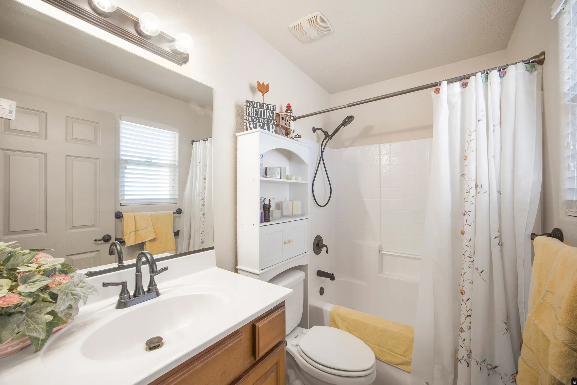 Bathroom featuring a vanity with a white countertop and wood-finish cabinetry, a bronze-finish faucet, and a shower-over-tub combination with white subway tile surround