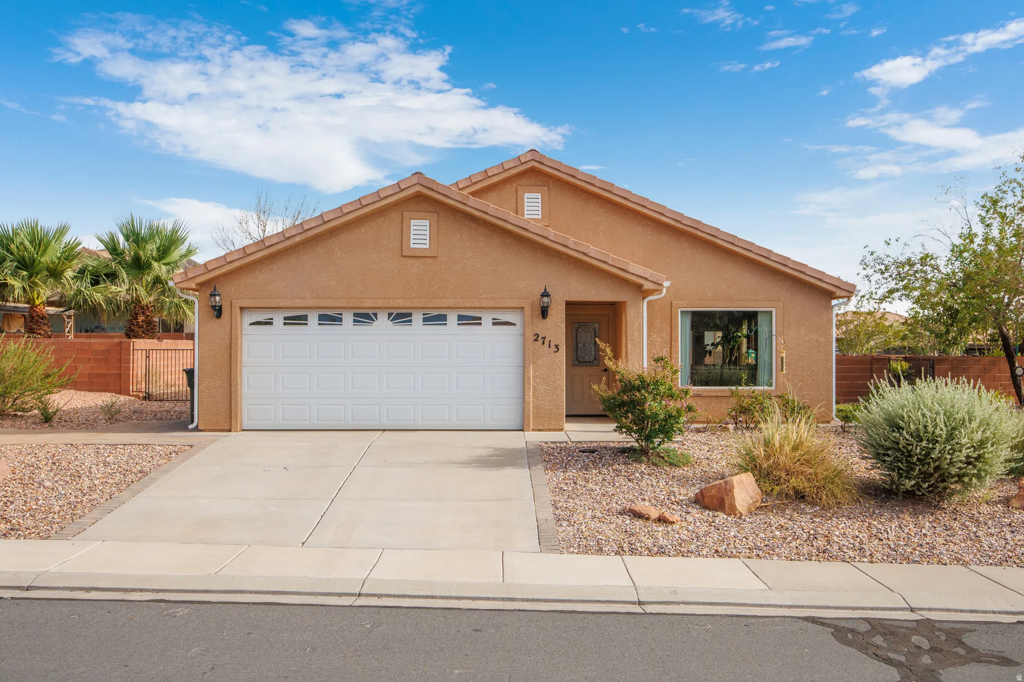 Sienna-toned stucco exterior with a tile roof and an attached two-car garage