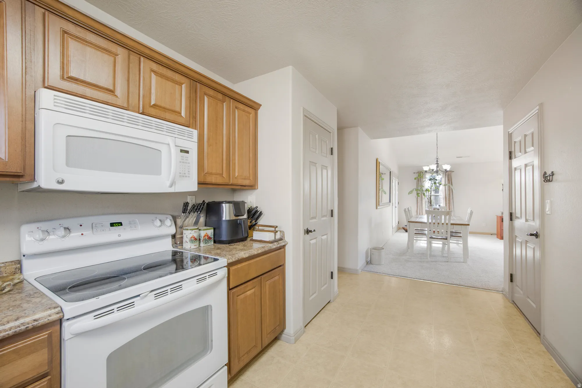 Kitchen featuring wood cabinetry, solid surface countertops, white range, and over-the-range microwave