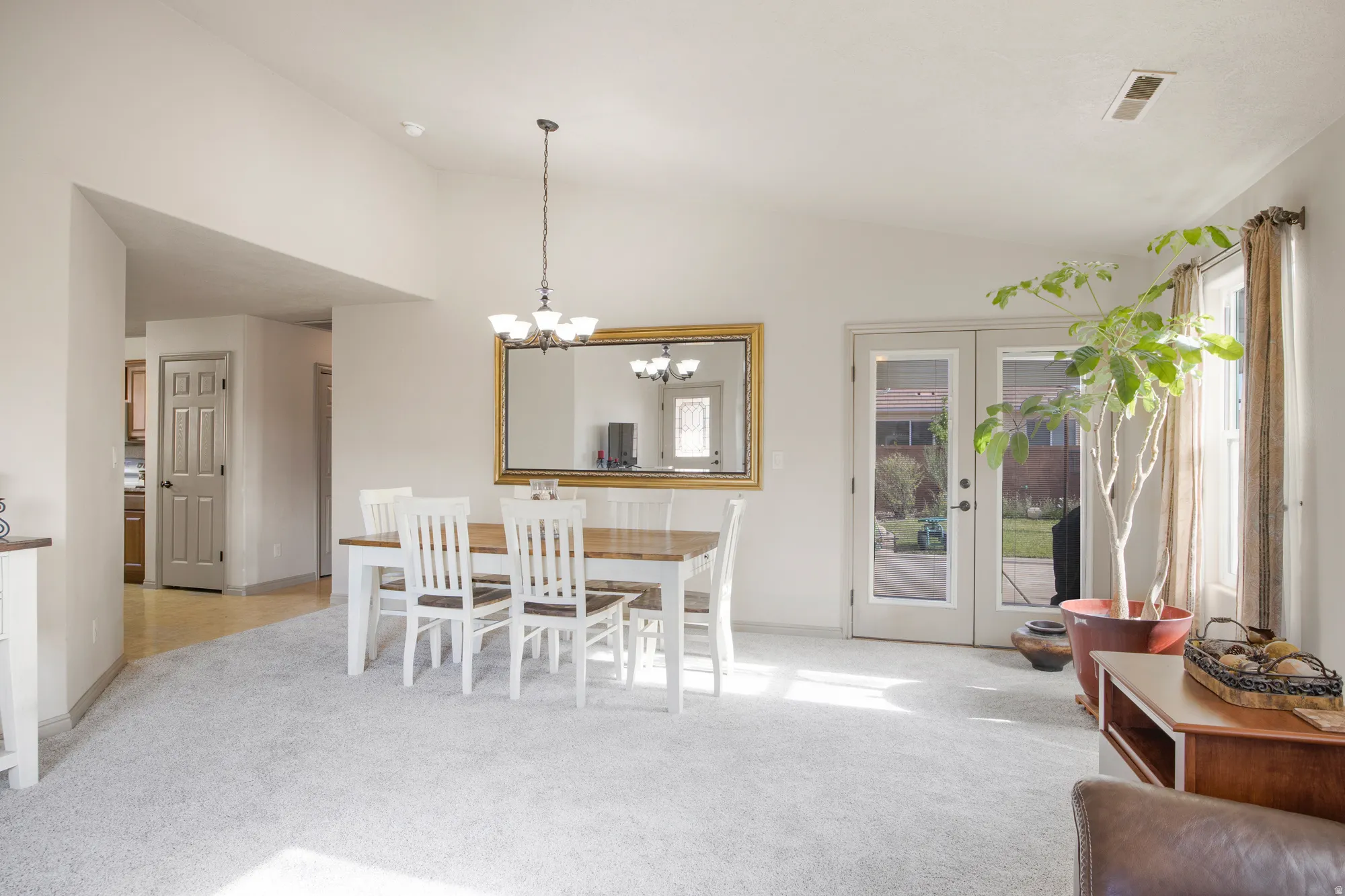 Spacious open-concept room featuring light-toned carpeting and vaulted ceilings