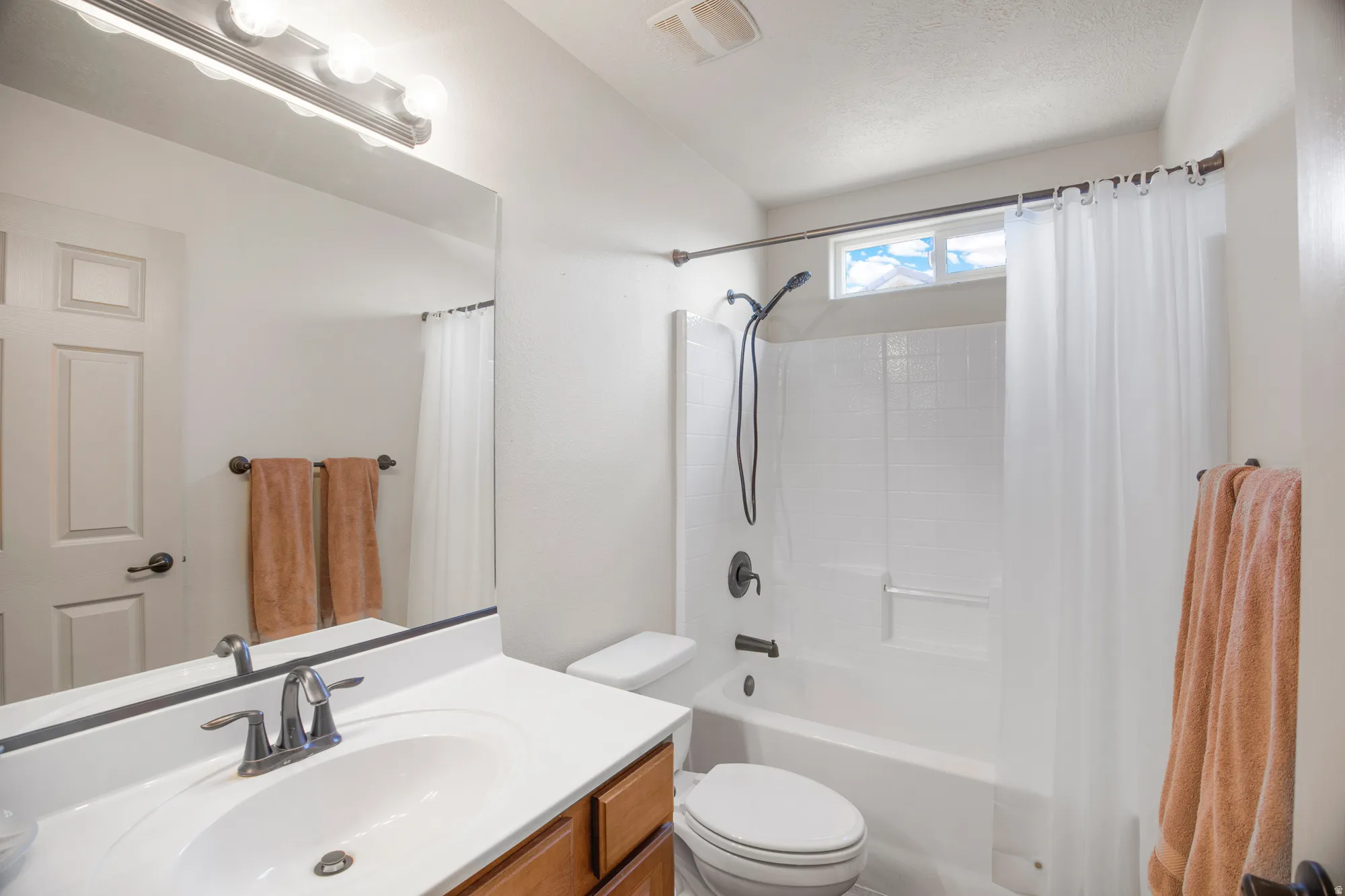 Bathroom featuring a single vanity with wood-finish cabinetry, white countertop, and an undermount sink