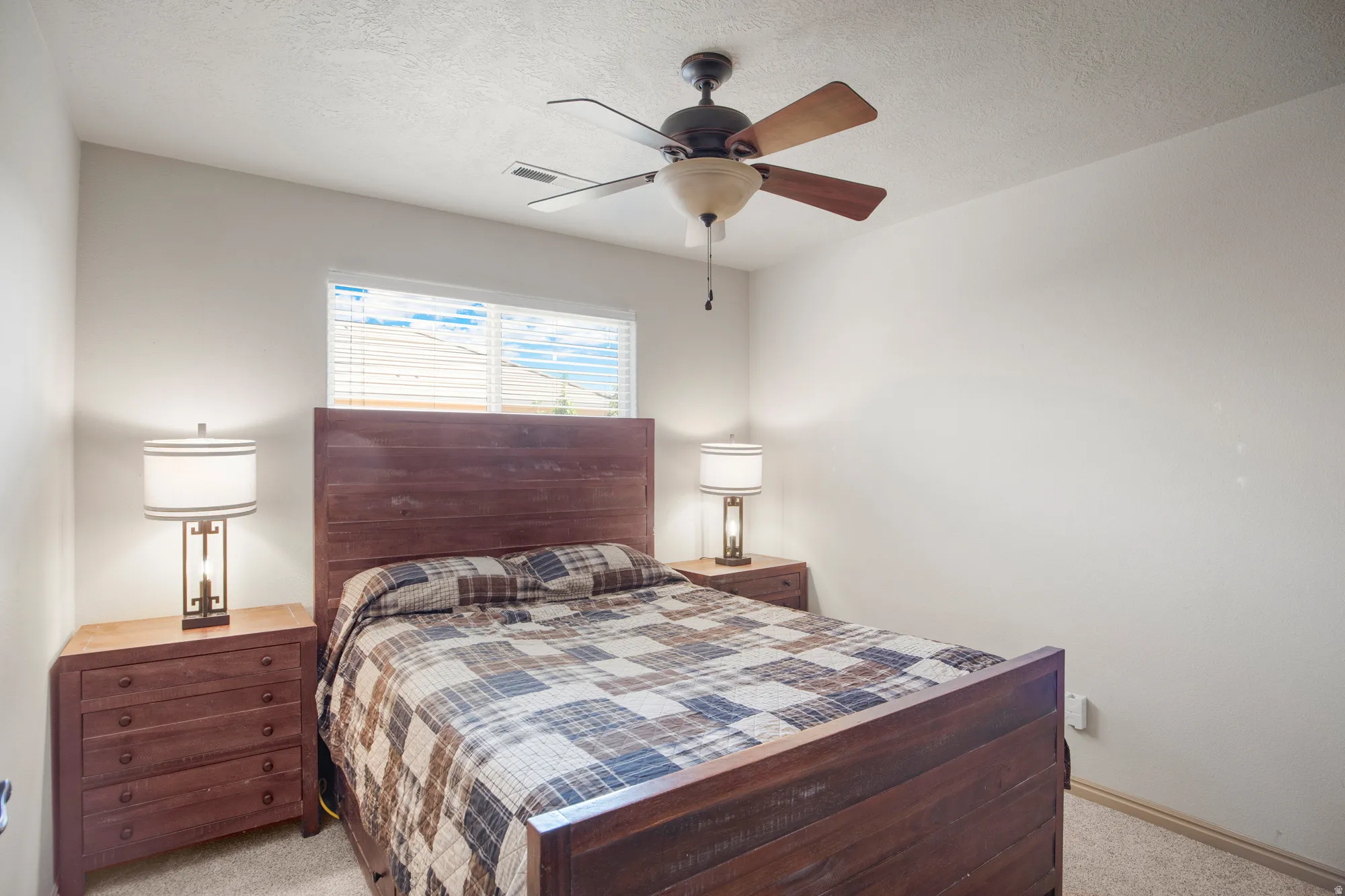 Bedroom featuring a ceiling fan with light fixture, window with blinds, and light-colored carpeting