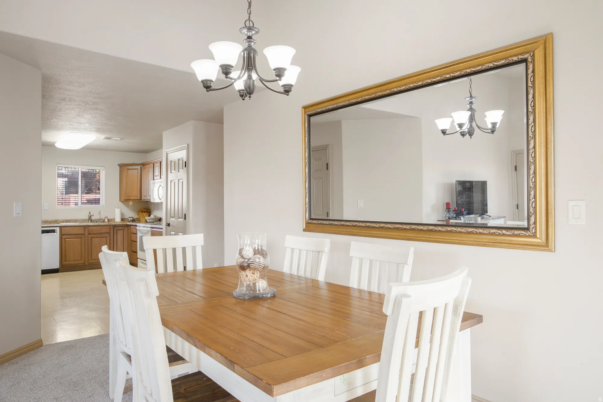 Dining area featuring a five-light chandelier, a large framed wall mirror, and a wood-finish dining table