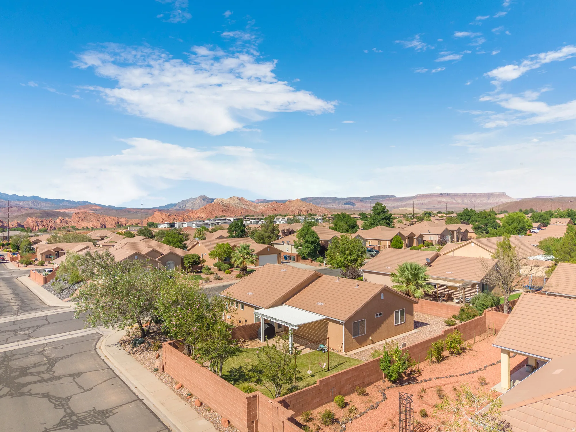 Residential neighborhood with single-story homes featuring tan stucco exteriors and terra cotta tile roofs