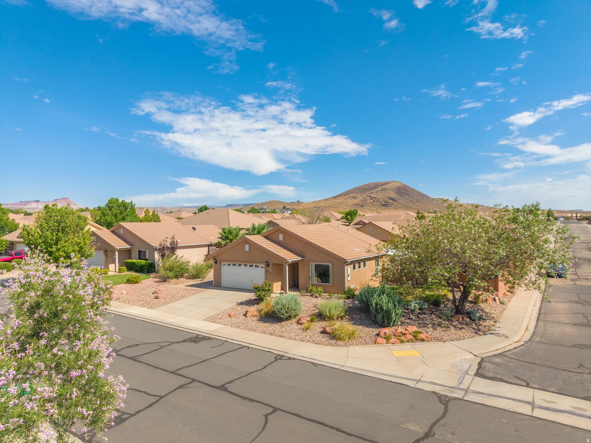 Corner lot property featuring a light brown stucco exterior, an attached two-car garage, and a concrete driveway