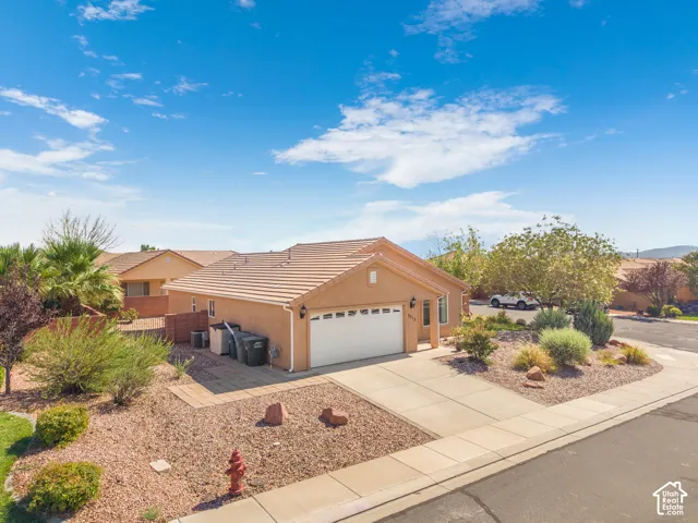 Single-story stucco residence featuring a tile roof and an attached garage