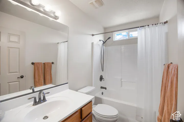 Bathroom featuring a single vanity with wood-finish cabinetry, white countertop, and an undermount sink