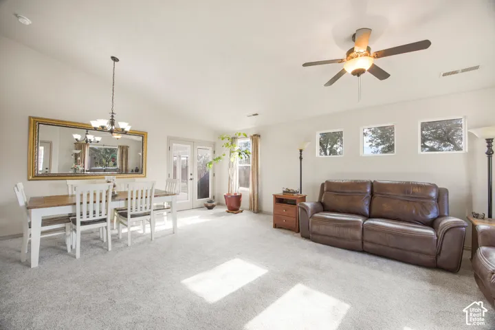 Open-concept living space featuring vaulted ceilings, a ceiling fan with integrated lighting, and light-toned carpeting