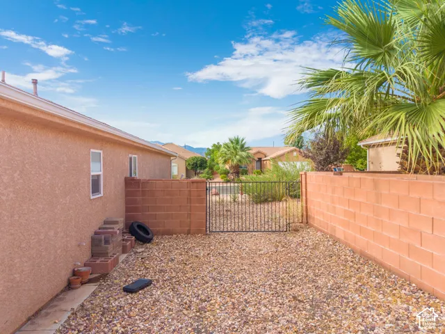 Gravel yard featuring a block wall, wrought iron gate, and stucco exterior