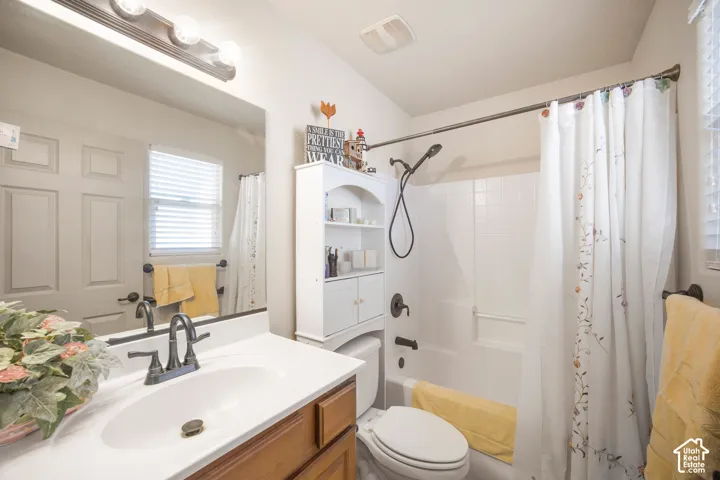Bathroom featuring a vanity with a white countertop and wood-finish cabinetry, a bronze-finish faucet, and a shower-over-tub combination with white subway tile surround