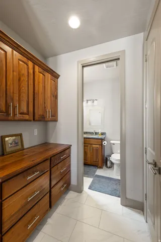 Built-in wood cabinetry with chrome hardware, wood-finish countertop, and white rectangular tile flooring