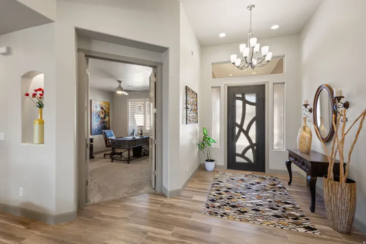 Entryway with wood-finish tile flooring, a decorative front door with opaque glass details, and a chandelier lighting fixture