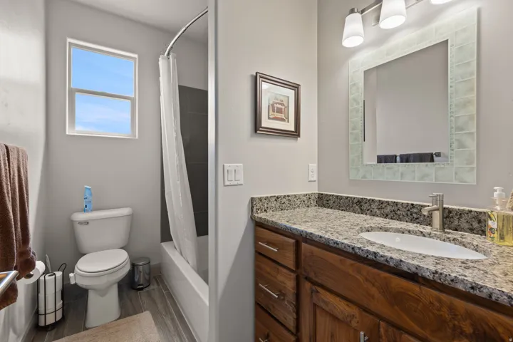 Bathroom featuring a wood-finish vanity with a granite countertop, undermount sink, and brushed nickel faucet