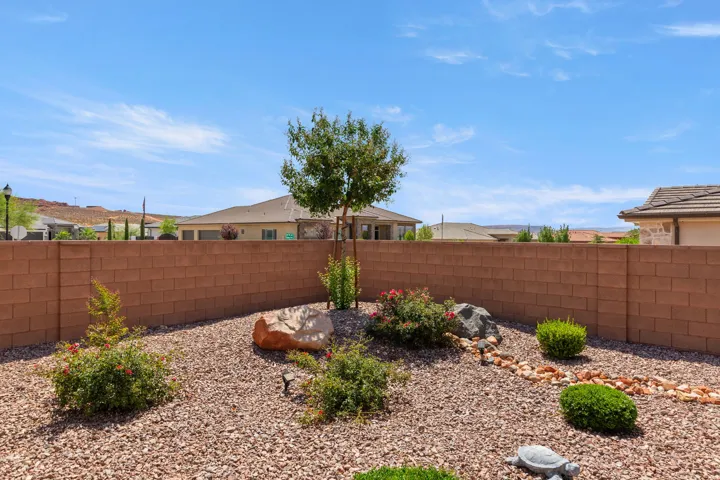 Enclosed backyard featuring a block wall, gravel landscaping, and established plantings