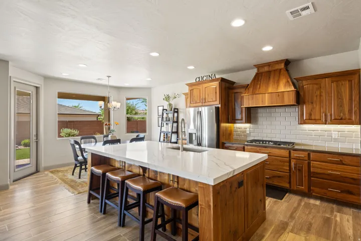 Spacious kitchen featuring a large island with a light-colored countertop, rich wood-finish cabinetry, stainless steel appliances, and wood-finish flooring