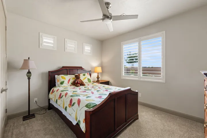 Bright bedroom featuring a ceiling fan, plush carpet, and light gray walls