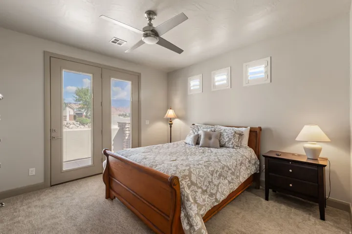Neutral-toned room featuring a ceiling fan, plush carpet flooring, and a private balcony accessed through double French doors